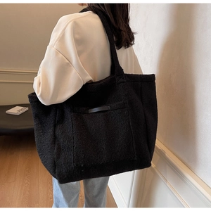 Detail shot of a black fuzzy lamb wool tote bag worn over the shoulder for winter style