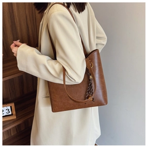 Sac fourre-tout vintage marron avec charm en soie porté sur un manteau beige élégant