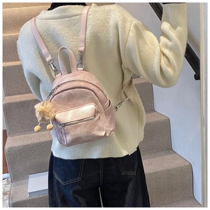 Detail van een lichtroze lederen mini-rugzak met pluche pompon op vrouwelijk model