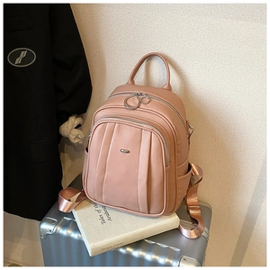 Detailansicht eines altrosa Rucksacks mit drei Reißverschlüssen auf einem Koffer