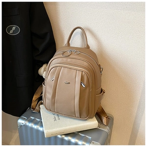Detail eines Lederrucksacks mit Litschi-Muster auf silbernem Koffer mit Metallakzenten