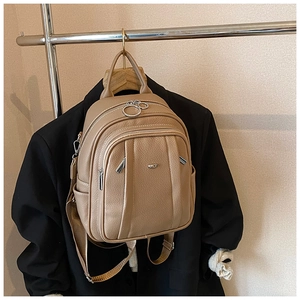 Detail eines khakifarbenen Lederrucksacks mit Metallreißverschlüssen am Sakko