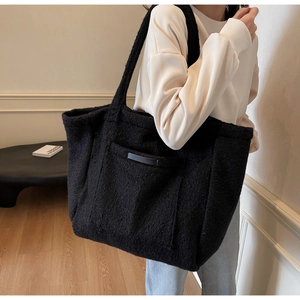 Detail view of large black plush tote bag showing soft sherpa texture and shoulder strap