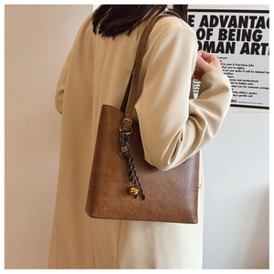 Sac cabas en cuir marron avec une breloque décorative en corde et boule dorée chic