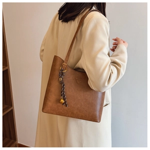 Vue détaillée latérale du sac fourre-tout marron vintage avec pendentif tressé