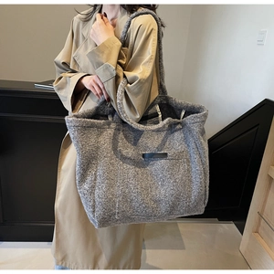Macro detail of high-capacity grey tweed tote bag with black leather accents for autumn