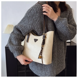 Détail du sac cabas crème avec bandoulière marron et breloque clochette tissée