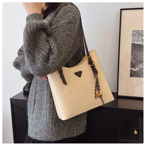 Détail du sac fourre-tout d'hiver crème avec bandoulière marron et logo métallique chic