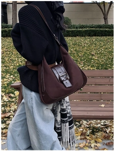 Detailed macro view of dark brown suede shoulder bag with polished leather trim and buckle
