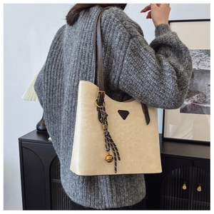 Vue détaillée du sac cabas crème avec son pendentif clochette décoratif et sa bandoulière