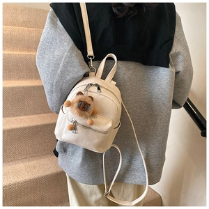 Detail van een beige PU-leren mini-rugzak met een schattige pluche leeuwen-sleutelhanger