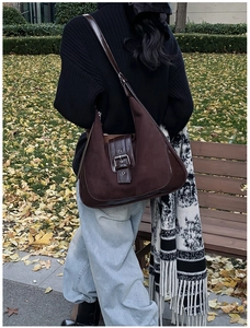 Chocolate brown hobo shoulder bag with matte finish and metal buckle detail in a park