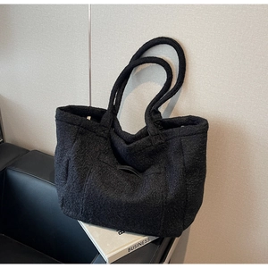 Detail shot of black fuzzy faux fur tote bag on a sofa showing soft plush material