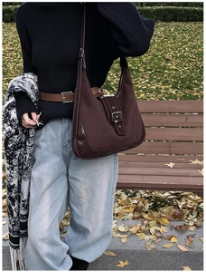 Detailed view of brown matte and polished leather patchwork underarm bag with metal buckle