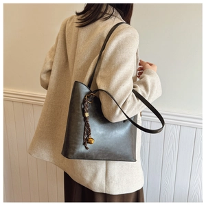 Détail du sac cabas gris foncé avec cordon noué et breloque sphérique dorée chic