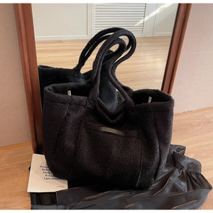 Detail view of the black wool tote bag featuring a textured outer pocket and wide strap