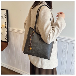 Détail d'un grand sac cabas vintage en similicuir mat foncé avec charm décoratif