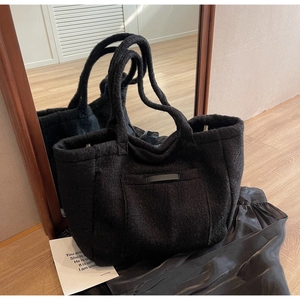 Detail of black faux shearling tote bag with fuzzy texture and sturdy handles