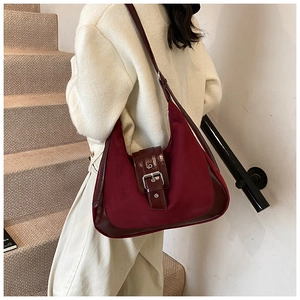 Detailaufnahme der burgunderroten Schultertasche mit Wildleder-Optik und Lackleder-Akzenten