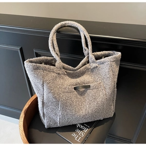 Close-up of grey tweed tote bag with a small black leather pocket on a wooden chair
