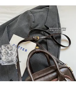 Détail de la bandoulière réglable en cuir et des boucles en bronze sur sac marron