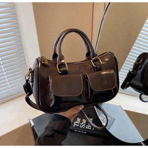 Detail of dark brown glossy Boston bag with double front pockets and gold hardware