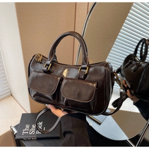 Detail of dark brown glossy leather handbag with front pockets and vintage metal hardware