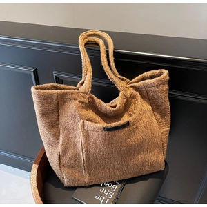 Detailed close-up of brown fuzzy tote bag texture with front pocket and leather tag