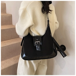 Detailansicht der schwarzen Hobo-Tasche aus Matt- und Lackleder am Model im Raum