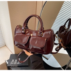 Detail of burgundy Boston bag showing front flap pockets and polished vintage hardware