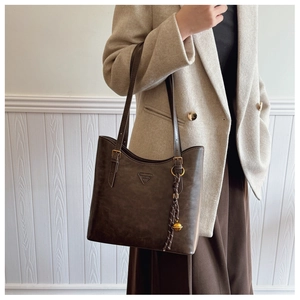 Détail du sac cabas vintage marron foncé avec texture en cuir et breloque à nœud
