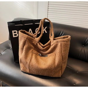 Detail of caramel plush tote bag with thick sheepskin texture and black leather trim