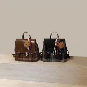 Dettaglio dello zaino in lana scozzese con patta in pelle e ciondolo a forma di orsetto