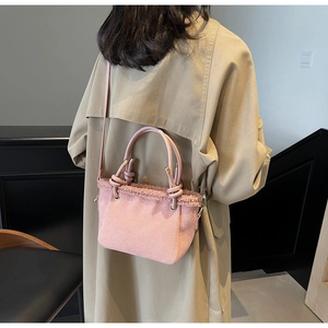 Detail of pink faux suede bucket bag with plush faux fur trim and knotted handle design