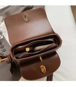 Interior view of brown leather crossbody bag with multiple compartments and bronze hardware