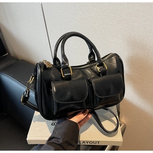 Detail of black glossy handbag with double front pockets and vintage gold hardware