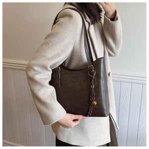 Détail du sac cabas marron foncé avec boucle décorative et pompon à clochette dorée