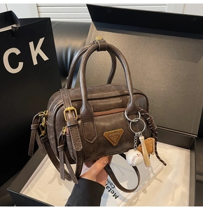 Gros plan du sac en cuir marron vintage avec plaque en métal et breloques