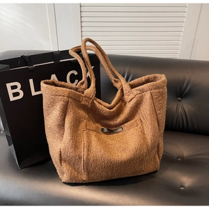 Detailed view of brown plush fleece tote bag texture with leather zipper pull detail