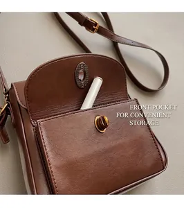 Close-up of brown leather crossbody bag with front pocket and gold twist lock closure