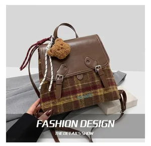 Dettaglio dello zaino vintage in lana scozzese con patta in pelle e ciondolo a orso