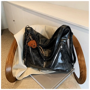 Close-up of black textured tote bag with metal zipper and a cute brown plush bear charm