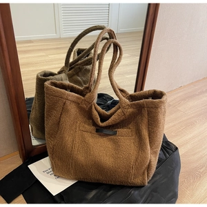 Detail of brown plush tote bag showing fuzzy wool texture and leather label on front pocket