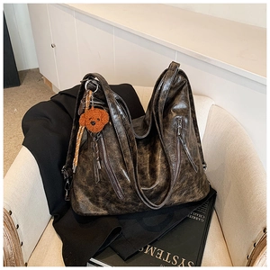 Detailed close-up of dark brown vintage oiled leather tote bag with plush bear charm