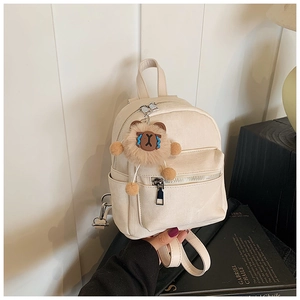 Detailweergave van mini beige rugzak met voorvak en schattige leeuw pluche hanger