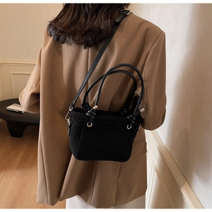Detail of black matte bucket bag featuring plush faux fur trim and knotted handles