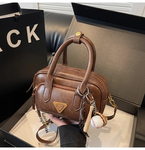 Détail du sac à main en similicuir marron avec breloque baseball et logo en boîte cadeau