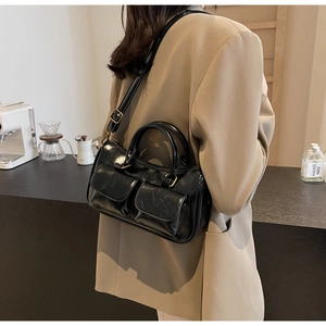 Close-up of a glossy black vintage doctor bag with dual pockets and metal buckle details