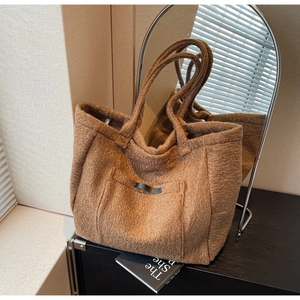 Detail view of dark brown plush teddy tote bag showing curly texture and front patch pocket