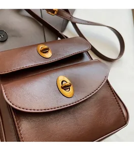 Detailed macro view of dark brown leather crossbody bag with dual golden twist locks